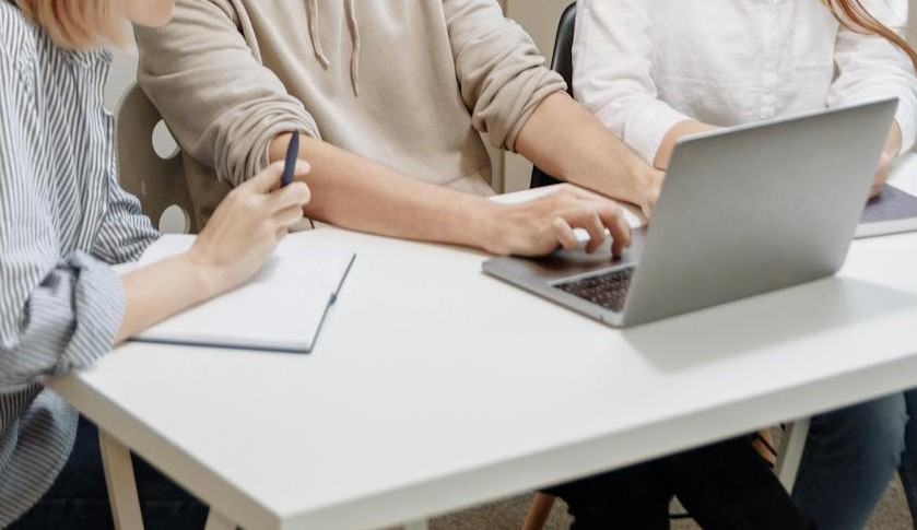 Die Conversion Optimierung verständlich erklärt 1 Drei Personen sitzen vor einem Laptop an einem Arbeitstisch und arbeiten gemeinsam