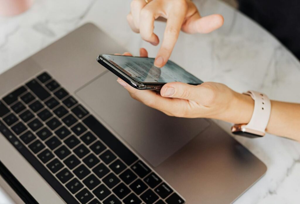 Personal Branding für Führungskräfte 1 Eine Person scrollt am Handy, Laptop davor aufgeklappt