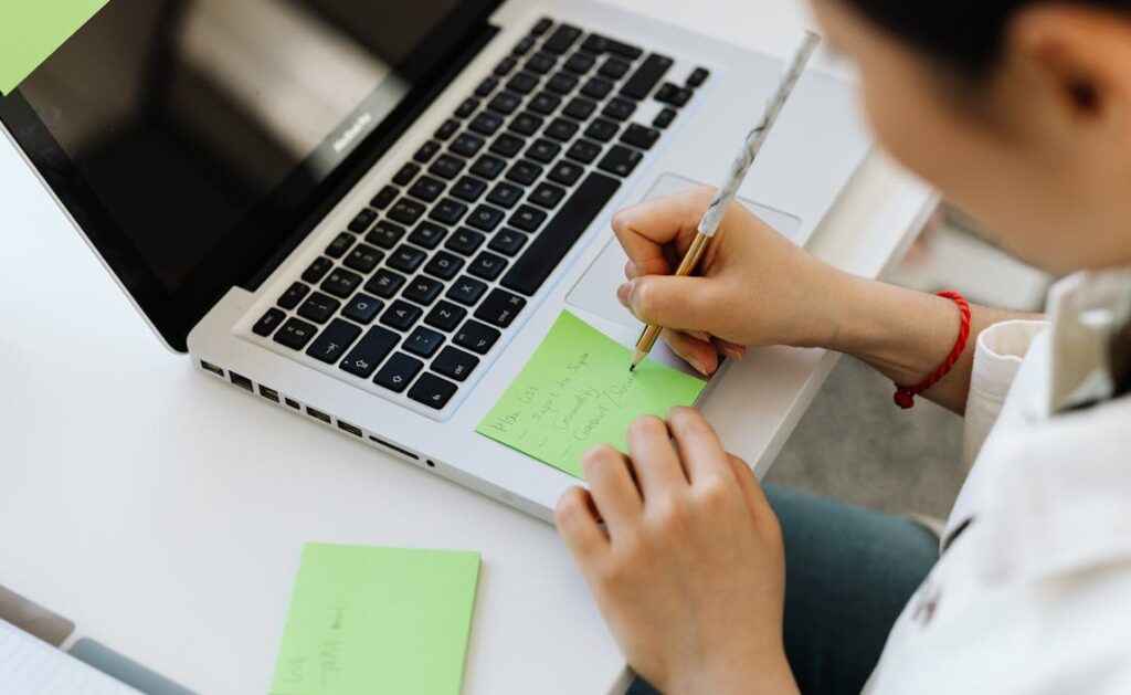 Personal Branding für Führungskräfte 2 Person schreibt sich Notizen auf, während ein Laptop davor offen steht