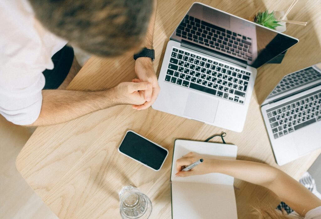 Employer Branding: Definition, Best Practices, Maßnahmen 5 Zwei Personen bei einer Besprechung mit zwei Laptops und einem Notizblock