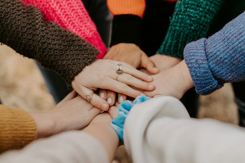 Employer Branding: Definition, Best Practices, Maßnahmen 7 Eine Gruppe von Händen eines Teams, die zusammen aufeinander gelegt werden