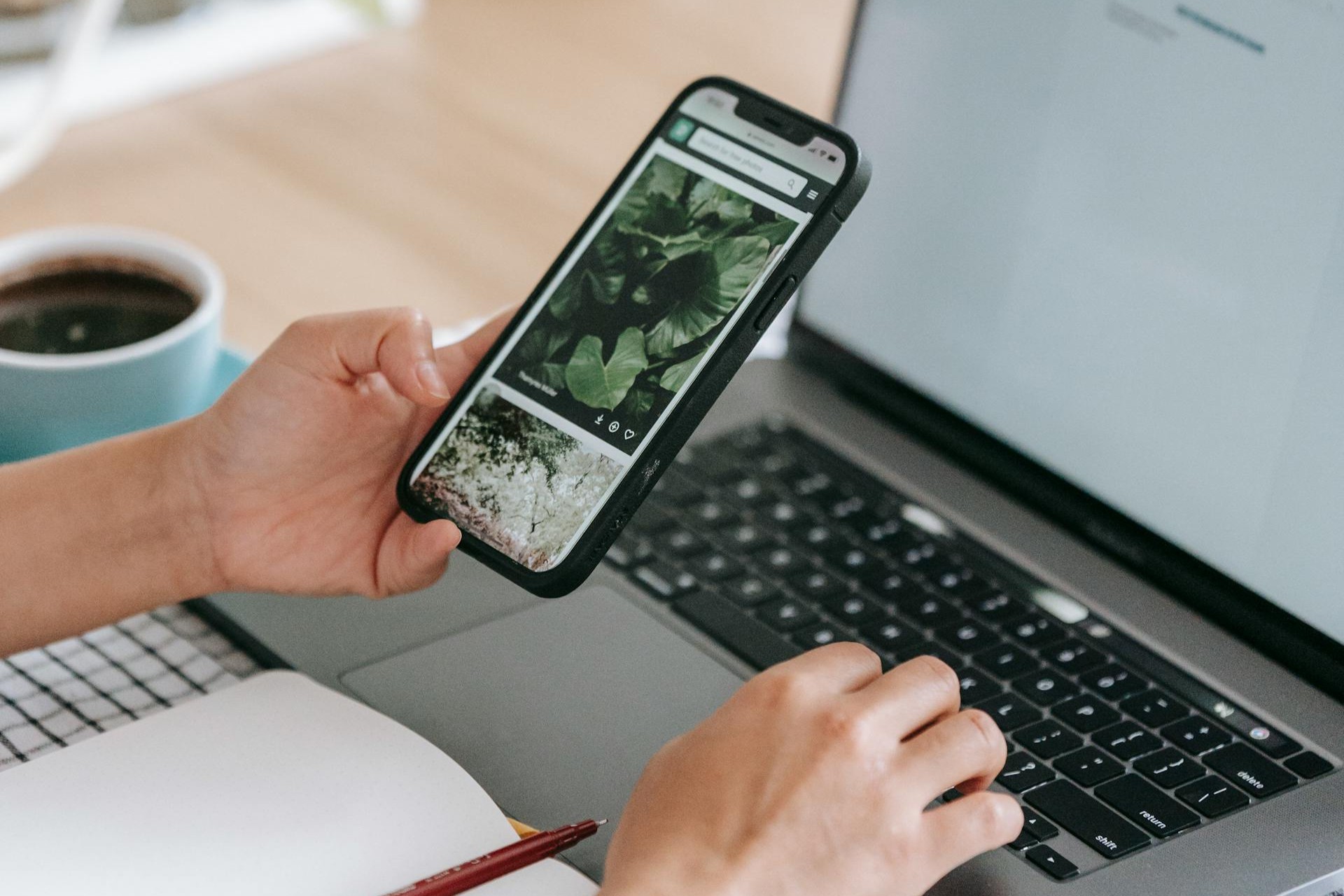 Person vergleicht Inhalte auf dem Handy und auf dem Laptop