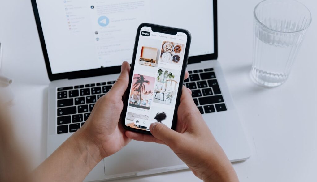Content Marketing einfach erklärt 2 Person tippt am Handy, dahinter aufgestellt ein Laptop