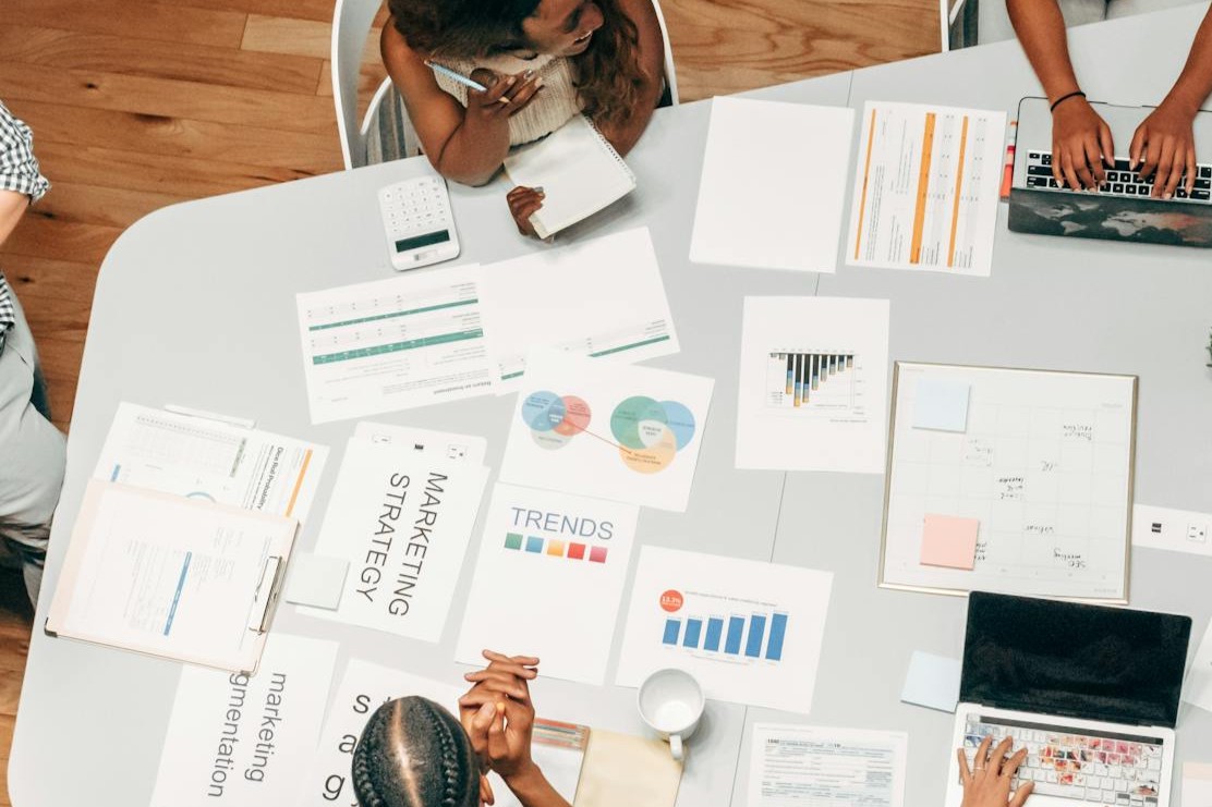 Marketing Team bespricht auf einem Arbeitstisch SEO Maßnahmen mit diversen Dokumenten