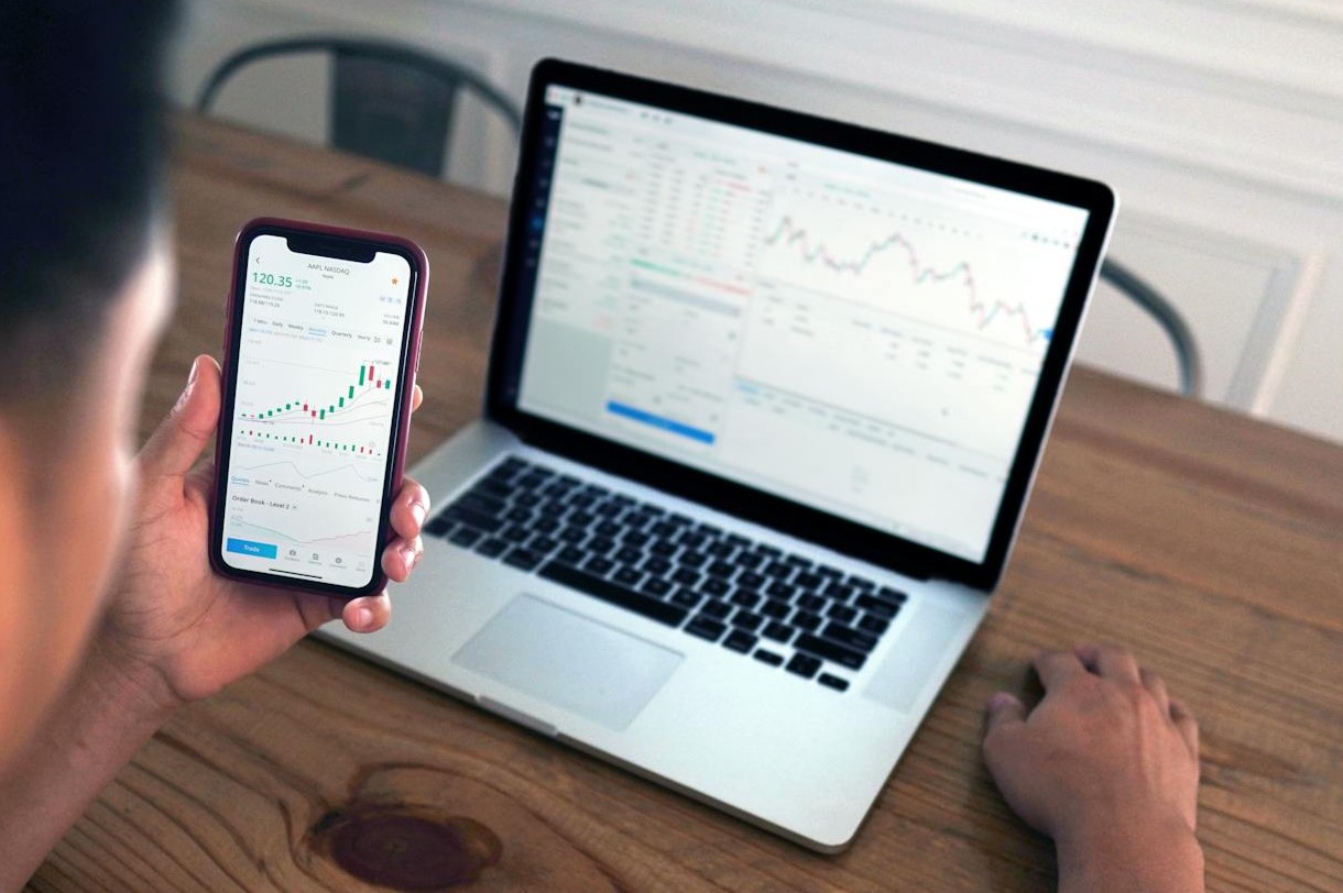 Laptop und Handy vor einer Person mit Google Analytics Daten