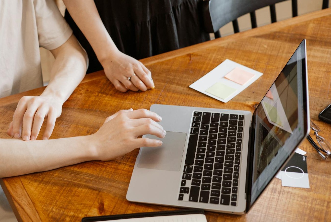 zwei personen stehen zusammen an einem tisch und sehen sich etwas auf einem laptop an